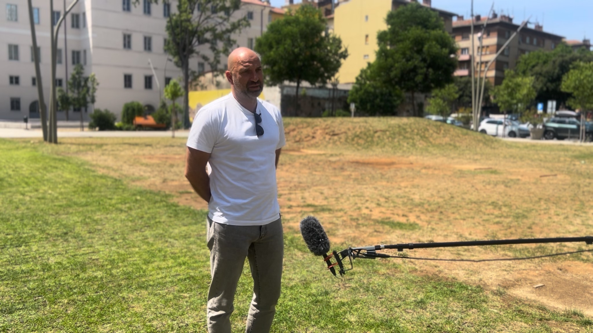 Outdoor interview on a green field with a microphone, promoting a sailing project focused on environmental protection